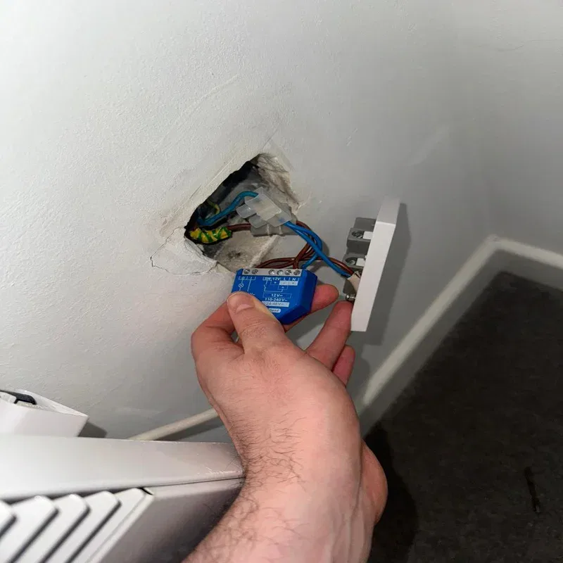 BuildSpark electrician London inspecting a blue smart relay in a wall during fault finding for no power to a radiator.