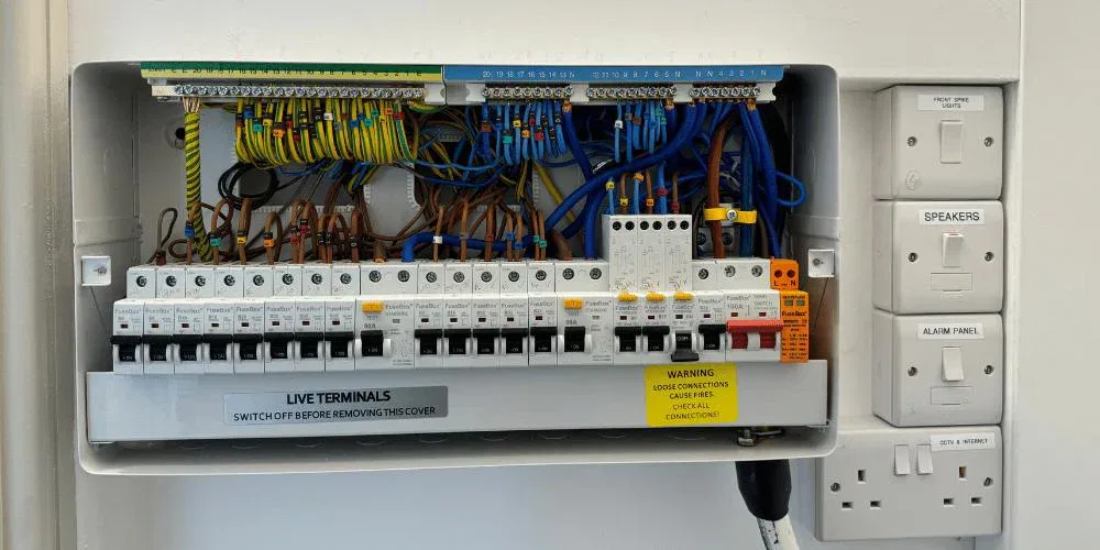 Open electrical fuse box with circuit breakers and coloured wiring installed by BuildSpark electrician Wimbledon