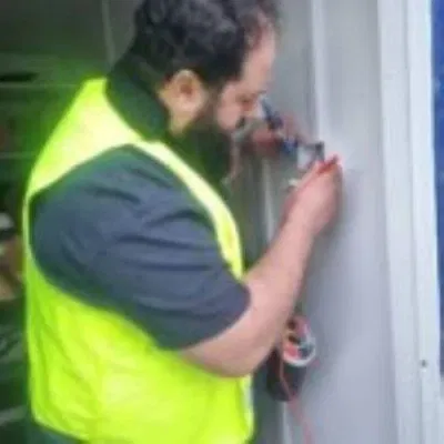 BuildSpark electrician Beni performing electrical inspection and testing on a commercial property in Hounslow, checking wiring and switches for EICR compliance.