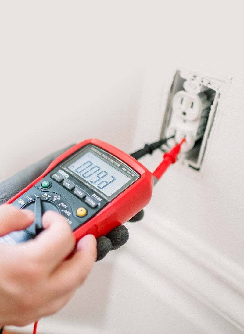 Electrician testing a socket in Balham using a multimeter Qualified electrician in Balham testing a wall socket with a digital multimeter during an electrical safety inspection.