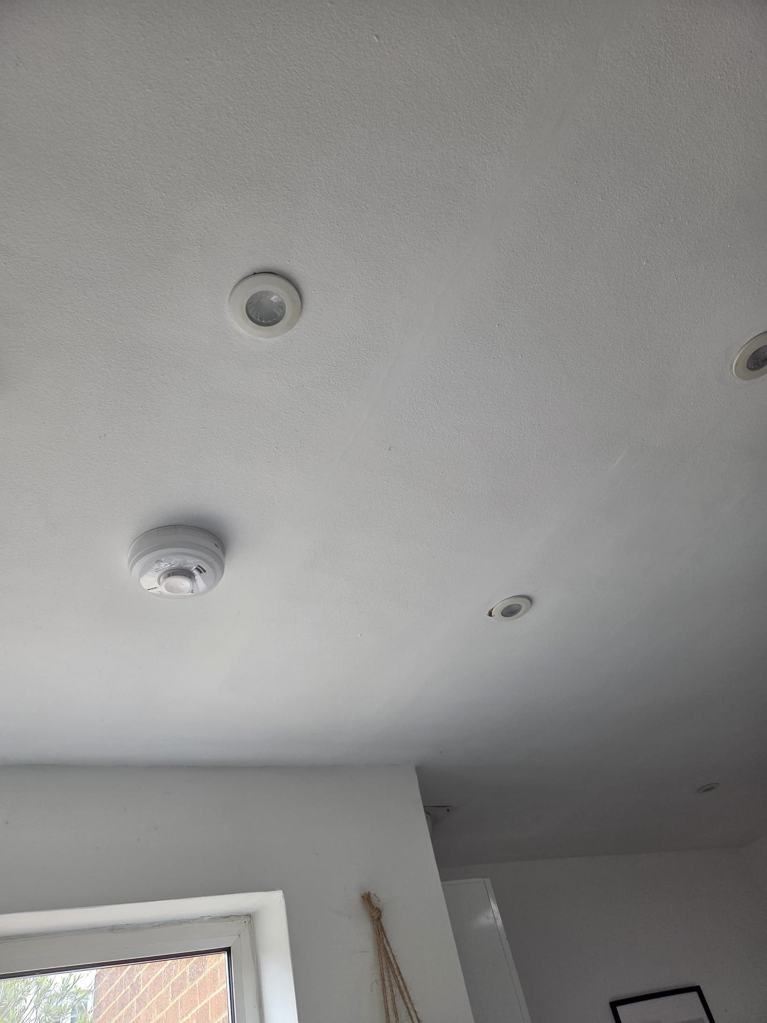 Modern ceiling with recessed spotlights and smoke alarm installation by BuildSpark London White plastered ceiling featuring recessed LED spotlights and a smoke alarm installed in a modern London property by BuildSpark electricians.