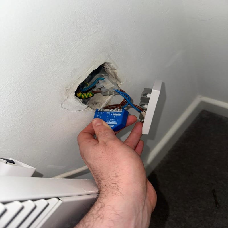 BuildSpark electrician London diagnosing no power to radiator smart relay BuildSpark electrician London inspecting a blue smart relay in a wall during fault finding for no power to a radiator.