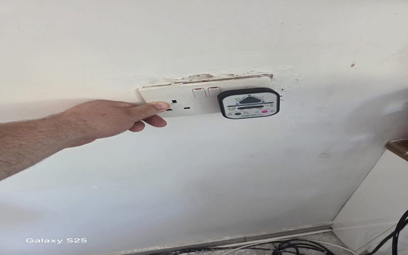 Electrical Fault Finding Cheam SM2 | BuildSpark Diagnostics An electrician using a Kewtech Loopcheck 107 plug-in socket tester on a double wall outlet to check wiring polarity and ring circuit continuity during a domestic fault finding job, referenced as fault finding cheam.jpeg.