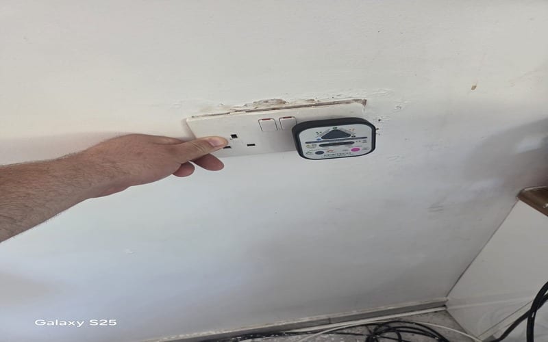 Electrical Fault Finding Cheam SM2 | BuildSpark Diagnostics An electrician using a Kewtech Loopcheck 107 plug-in socket tester on a double wall outlet to check wiring polarity and ring circuit continuity during a domestic fault finding job, referenced as fault finding cheam.jpeg.